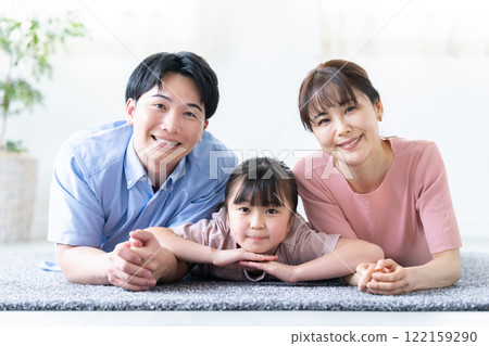 A family of three lying down in the living room A family of three lying down in the living room 122159290