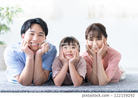 A family of three lying down in the living room A family of three lying down in the living room 122159292