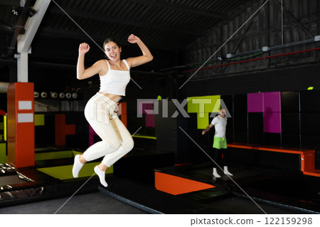 Girl acrobatic athlete jumping and exercising on trampoline indoors, modern hobby and fitness concept 122159298