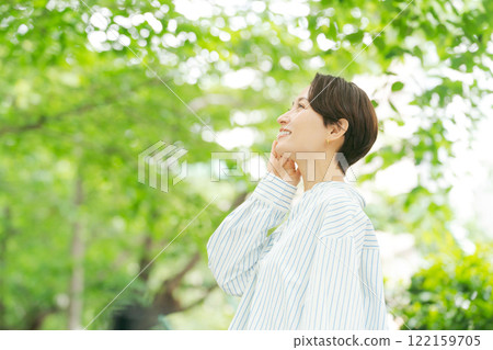 A woman with her hand on her cheek amidst fresh greenery A woman with her hand on her cheek amidst fresh greenery 122159705
