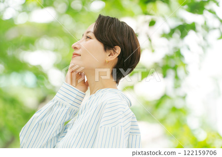 一個女人把手放在臉頰上,在新鮮的綠色植物中 一個女人把手放在臉頰上,在新鮮的綠色植物中 122159706