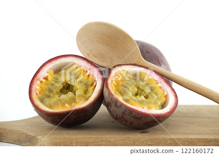 Two Halves of Passion Fruit Showing Seeds and Pulp Resting on Wooden Cutting Board with Spoon Two Halves of Passion Fruit Showing Seeds and Pulp Resting on Wooden Cutting Board with Spoon 122160172