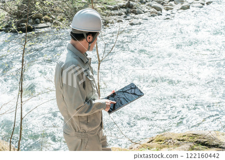 A male construction management engineer in work clothes conducting river surveys and water quality surveys in rivers and streams A male construction management engineer in work clothes conducting river surveys and water quality surveys in rivers and streams 122160442