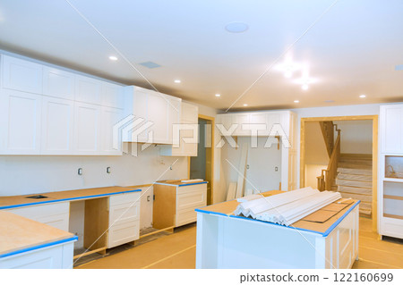 Kitchen in progress with white cabinets, bare countertops, scattered tools shows ongoing renovation work. 122160699