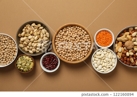 Beans, nuts and seeds in bowls on beige background, top view 122160894