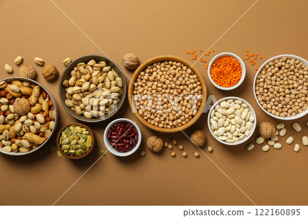 Beans, nuts and seeds in bowls on beige background, top view Beans, nuts and seeds in bowls on beige background, top view 122160895