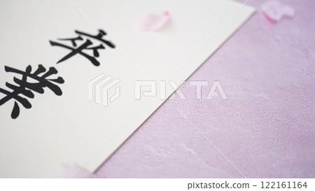Graduation lettering and a background of cherry blossom petals on a pink background Graduation lettering and a background of cherry blossom petals on a pink background 122161164