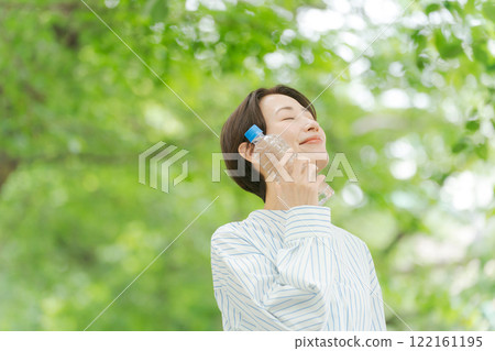 A woman drinking water in fresh green 122161195