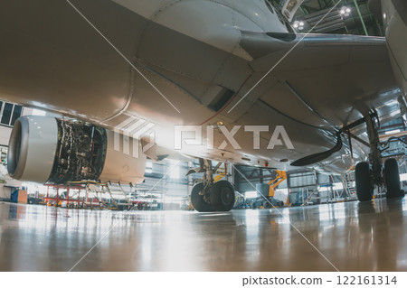Close-up of the lower fuselage of a white passenger jet plane in an aircraft hangar. Airplane under maintenance. Checking mechanical systems for flight operations 122161314