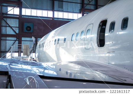 Close-up of a white passenger jet plane in the hangar. Airplane under maintenance. Checking mechanical systems for flight operations 122161317