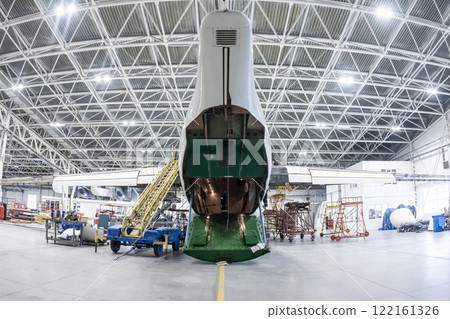 Rear view of a transport airplane with open cargo bay in an aviation hangar. Aircraft under maintenance. Checking mechanical systems for flight operations Rear view of a transport airplane with open cargo bay in an aviation hangar. Aircraft under maintenance. Checking mechanical systems for flight operations 122161326