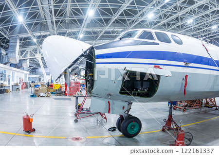 White transport turboprop airplane in the hangar. Aircraft under maintenance. Checking mechanical systems for flight operations 122161337