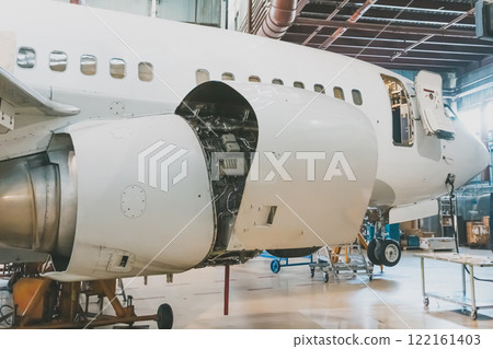 White passenger jet plane in the airplane hangar. Airliner under maintenance. Checking mechanical systems for flight operations 122161403