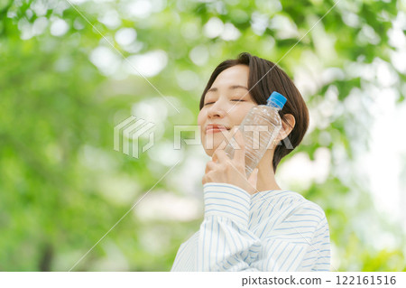 A woman drinking water in fresh green A woman drinking water in fresh green 122161516