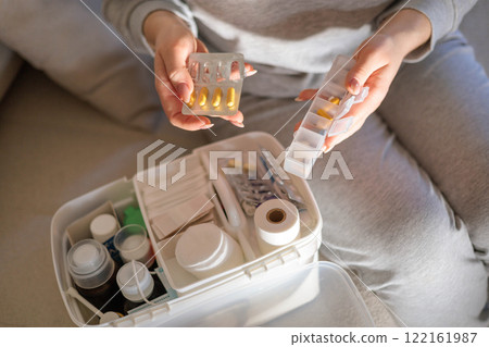 Closeup female hand neatly placing medicament at domestic first aid kit top view. Closeup female hand neatly placing medicament at domestic first aid kit top view. 122161987