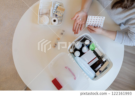 Female hands hold a pink round pill. The woman is going to take medicine for headaches, stomach pain Female hands hold a pink round pill. The woman is going to take medicine for headaches, stomach pain 122161993