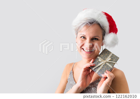 An elderly middle-aged lady with gray hair and a short haircut smiles and holds a gift. 122162010