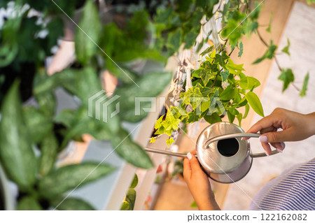 Unrecognizable woman gardener florist growing care use watering can at home indoor garden closeup 122162082