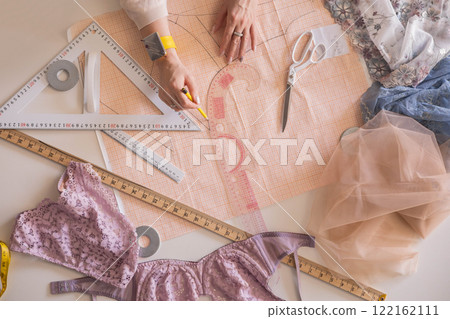 A woman seamstress designs and draws a pattern for underwear on graph paper. A woman seamstress designs and draws a pattern for underwear on graph paper. 122162111