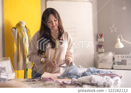 A woman seamstress designs and draws a pattern for underwear on graph paper.  122162112