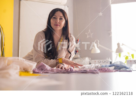 A woman seamstress designs and draws a pattern for underwear on graph paper. A woman seamstress designs and draws a pattern for underwear on graph paper. 122162118