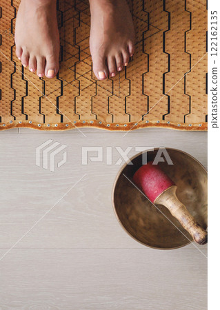 Yoga woman legs standing on nails with singing meditation bowl top view closeup Yoga woman legs standing on nails with singing meditation bowl top view closeup 122162135