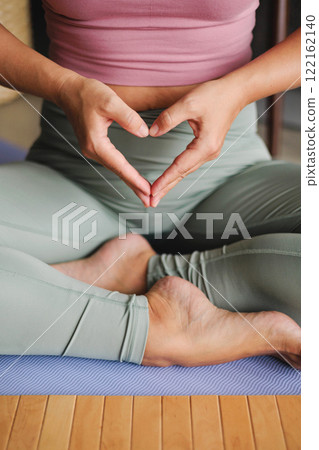 Yoga woman in lotus position with hands heart shape closeup. Yogi spiritual female asana with love 122162140