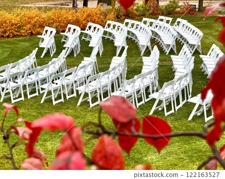 white chairs in a semicircle on grass surrounded by colorful autumn foliage 122163527
