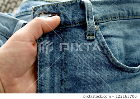 male hand holding blue jeans by the waistband male hand holding blue jeans by the waistband 122163706
