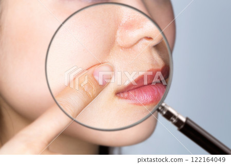 一名年輕女子的法令紋被放大鏡放大。 一名年輕女子的法令紋被放大鏡放大。 122164049