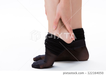一個穿著絲襪的女人正在觸摸她的腳跟。 122164050