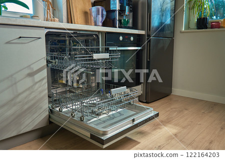 Open empty dishwasher with empty racks and extended basket in modern kitchen ready for loading. Home appliance 122164203