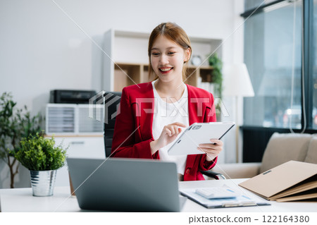 Asian businesswoman working with working notepad, tablet and laptop documents in the office Asian businesswoman working with working notepad, tablet and laptop documents in the office 122164380