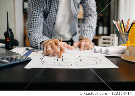 Creative architect projecting on the big drawings with architectural project at construction site at desk in office 122164714