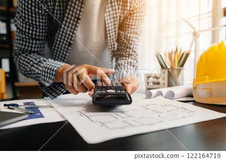 Engineer in helmet for workers security on office buildings and management on the construction drawing plan near laptop working in Engineering tools 122164719