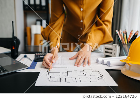 Engineer in helmet for workers security on office buildings and management on the construction drawing plan near laptop working in Engineering tools Engineer in helmet for workers security on office buildings and management on the construction drawing plan near laptop working in Engineering tools 122164720
