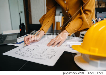 Engineer in helmet for workers security on office buildings and management on the construction drawing plan near laptop working in Engineering tools Engineer in helmet for workers security on office buildings and management on the construction drawing plan near laptop working in Engineering tools 122164721