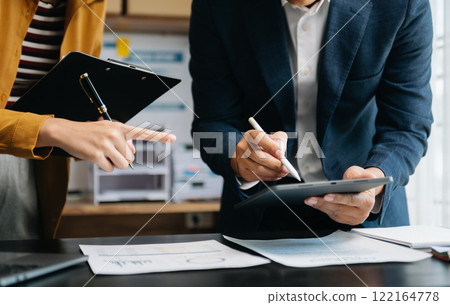 Businessman and team analyzing financial statement Finance task. with smart phone and laptop and  tablet. Wealth management concept in office 122164778