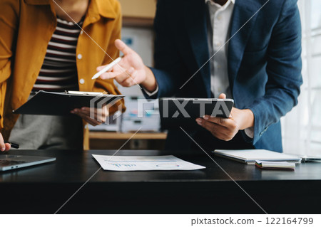 Businessman and team analyzing financial statement Finance task. with smart phone and laptop and  tablet. Wealth management concept in office 122164799