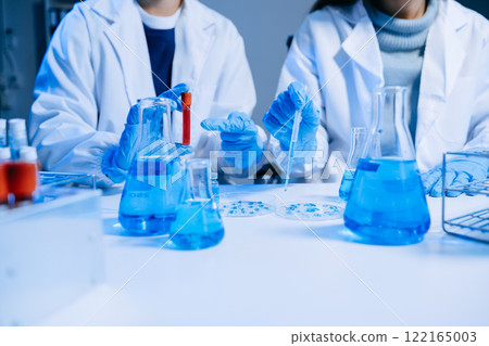 Two Scientist mixing chemical liquids in the chemistry lab. Researcher working in the chemical laboratory 122165003