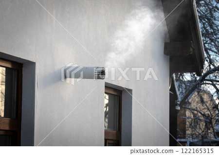 A smoking chimney from a gas boiler in a private house on a cold winter day 122165315