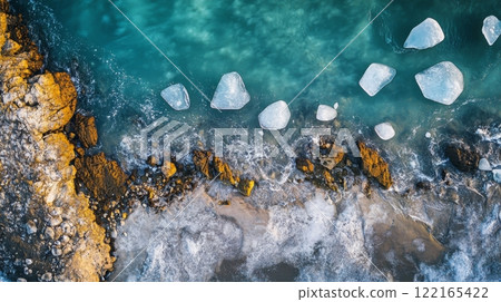 Aerial view of a stunning beach with icebergs along the shore. The vibrant blue ocean contrasts with rocky textures. A perfect serene landscape. Generative AI. 122165422