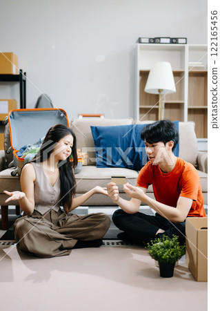 Asian young attractive couple man and woman use tablet and smartphone online shopping furniture decorate house with carton package move 122165456