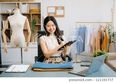 Successful fashion designer. Attractive young asian woman with smile while standing in workshop. Successful fashion designer. Attractive young asian woman with smile while standing in workshop. 122165737