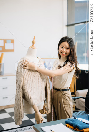 Successful fashion designer. Attractive young asian woman with smile while standing in workshop. Successful fashion designer. Attractive young asian woman with smile while standing in workshop. 122165738