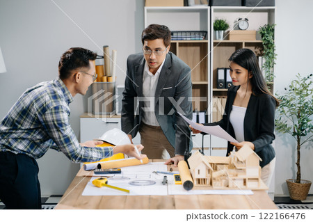 Engineer teams meeting working together wear worker helmets hardhat with on architectural project site and making model house. Engineer teams meeting working together wear worker helmets hardhat with on architectural project site and making model house. 122166476