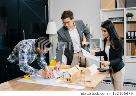 Engineer teams meeting working together wear worker helmets hardhat with on architectural project site and making model house. Engineer teams meeting working together wear worker helmets hardhat with on architectural project site and making model house. 122166479