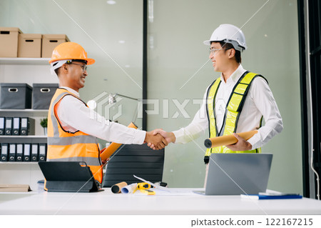 Contractor and architect looking at plan, tablet, laptop and talking about working on big project. Contractor and architect looking at plan, tablet, laptop and talking about working on big project. 122167215