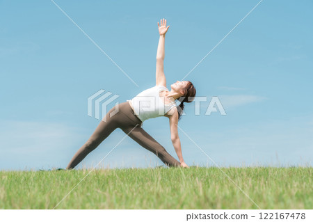Young Asian woman doing yoga, pilates and stretching under blue sky 122167478
