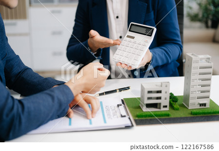 balancing the property sector The real estate agent is explaining the house style to see the house design and the purchase agreement. model house balancing the property sector The real estate agent is explaining the house style to see the house design and the purchase agreement. model house 122167586